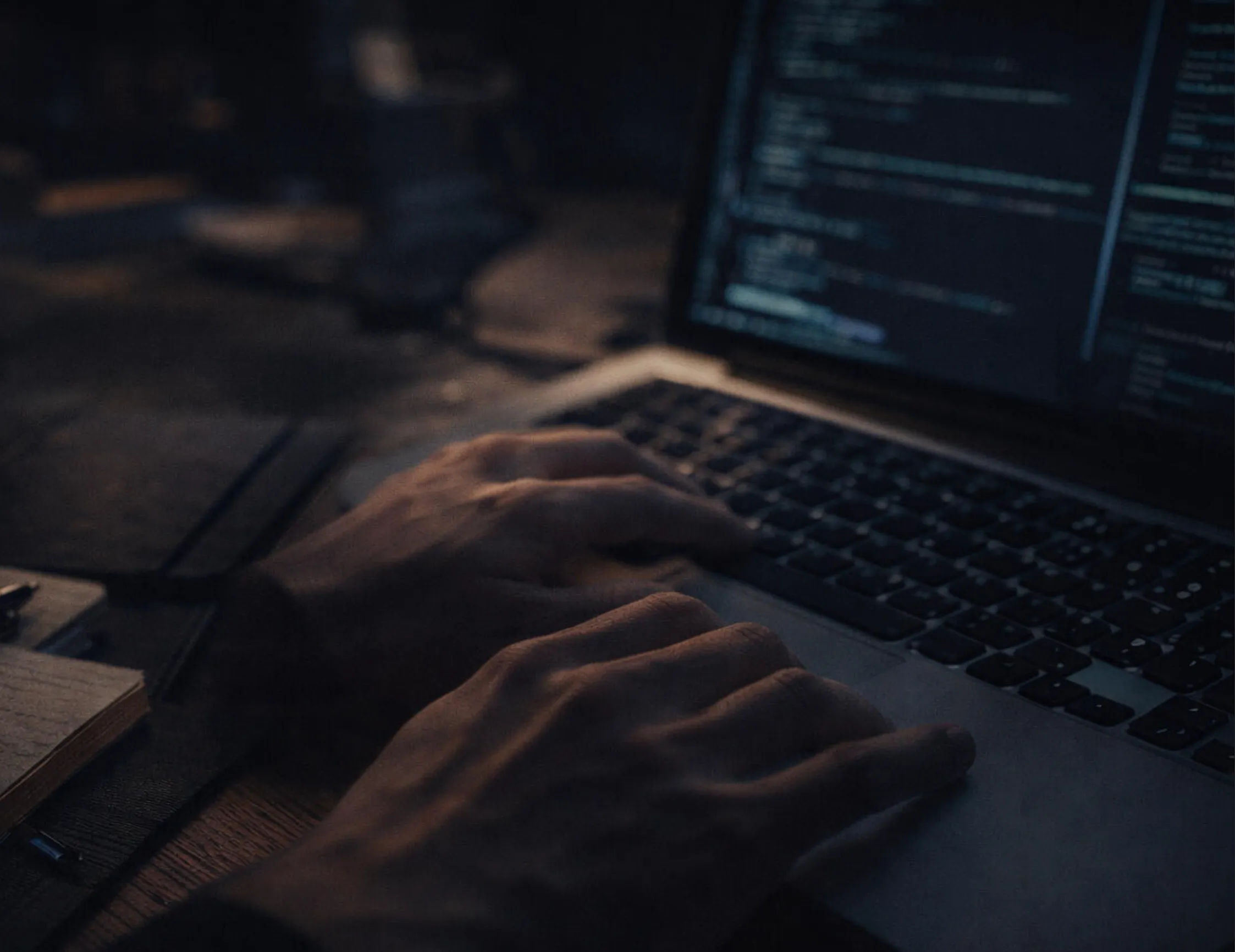 Hands typing on a keyboard in front of a screen showing program code